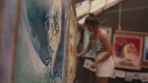 Beautiful artwork hangs on the walls, and a girl works in the background blurred.