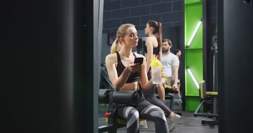 Full Length View of the Fitness Woman in Sportswear Sitting on the Bench with Bottle of Water and