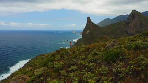 Girl Stands on Cliff Edge with Deep Ocean Mountain Range Aerial View on Cloudy Day