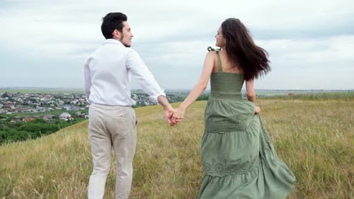 Happy Couple of Man and Woman Run Through Hilly Field
