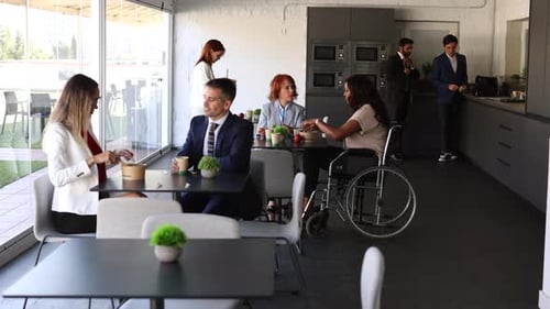 Business people talking and laughing during lunch break in a modern company cafeteria. A multi ethni