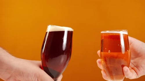 Closeup Clinking Cold Refreshing Light and Dark Beer in Slow Motion with White Foam Splashing Male