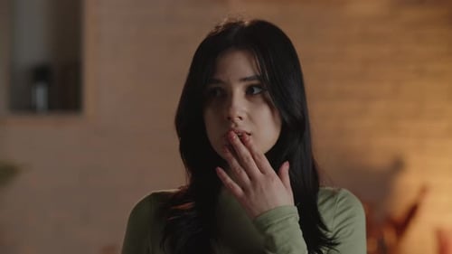 The Young Woman Screams in Surprise and Covers Her Mouth with Her Hand Looking Around Indoor Shot of