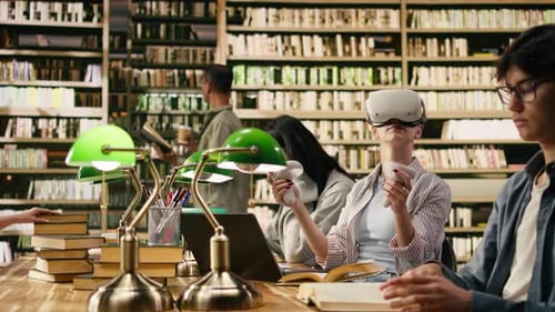 Student Wears VR Glasses and Holds Controllers in University Library