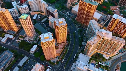 Hochhäuser, die mit orangefarbenem Licht des Sonnenuntergangs beleuchtet werden. Luftperspektive auf die Stadt über den Straßen.
