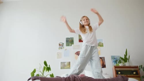 Happy Child Dancing on Bed with Headphones