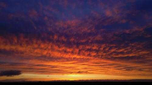 Beautiful calm orange purple pink blue sunset aerial with cumulus clouds