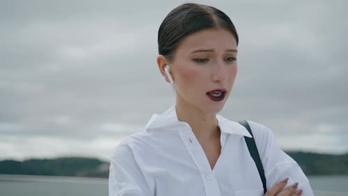 Woman Talking on Wireless Earphones Outdoors on Overcast Day