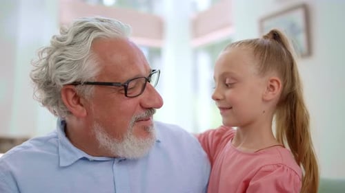 Loving Grandfather Hugging Granddaughter Indoors in Bright Home