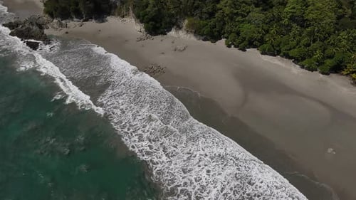 Aerial view of the waves entering the coast in a dark sand beach, Costa Rica