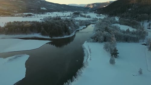 Stunning Aerial View of Winding River Through Snow Covered Forest