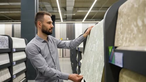 A Man in a Store Chooses Wallpaper for Home Concept of Repair and Shopping