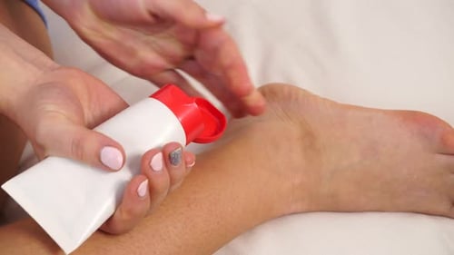 Woman Putting Ointment on Bad Ankle