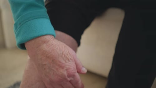 Old Woman in Green Applying Ointment to Arm in Peaceful Bedroom Setting