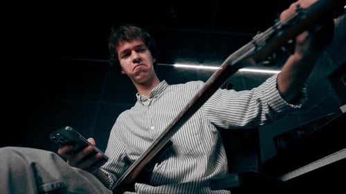 dans l'équipement de la salle d'enregistrement, le son de la musique, un beau jeune homme accorde une guitare, pince le