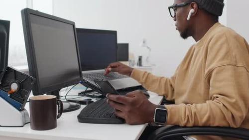 Programmierer nutzt Smartphone bei der Arbeit