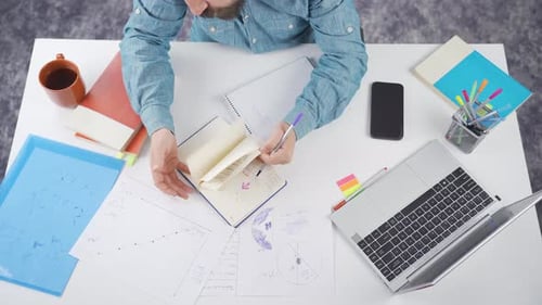 Adult Working at Desk With Notebooks and Laptop