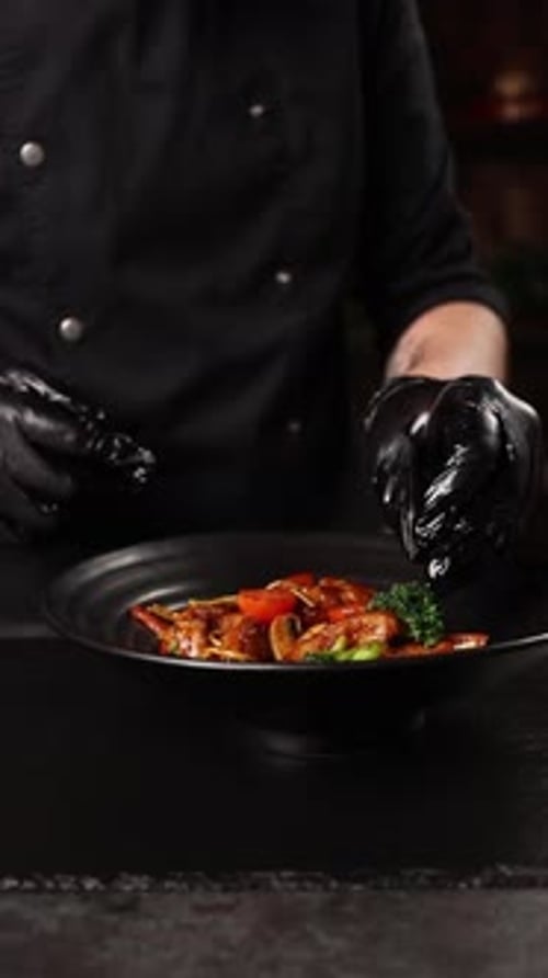 Chef adding garnish to stir fry in bowl
