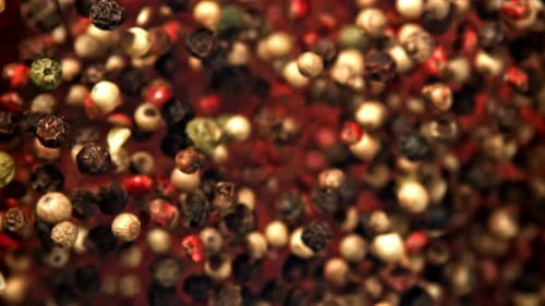 Mixed peppercorns falling and rotating in front of camera