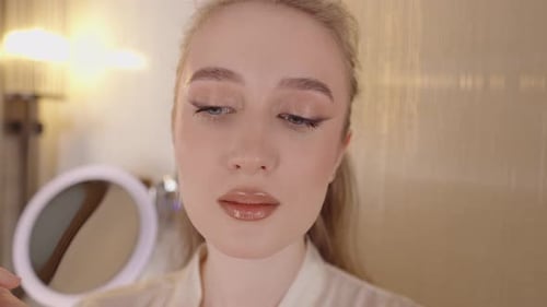 Young Woman Applies Lip Gloss in her Bathroom