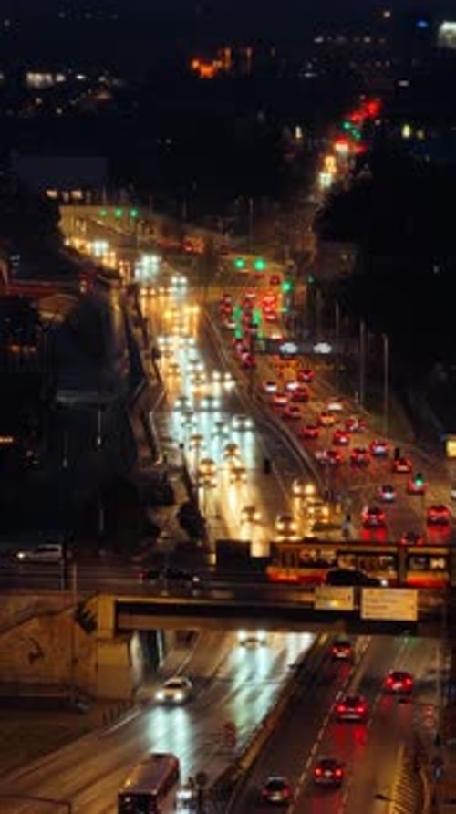 Aerial drone view of busy Warsaw traffic with cars and trams moving along illuminated city roads . V