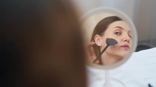 close-up portrait of a young girl in the mirror managing her makeup