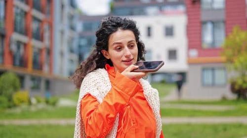 Smiling Woman Speaking Into Cellphone in Urban Setting