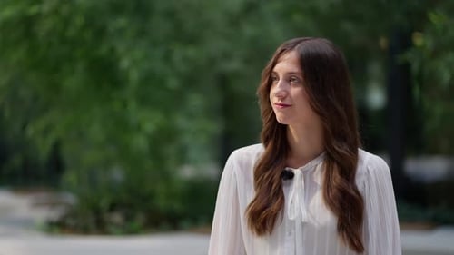 Young Woman in White Shirt Looks Thoughtful Outdoors
