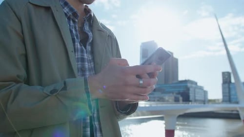 Young Man Typing Message on Phone Outdoors in the City
