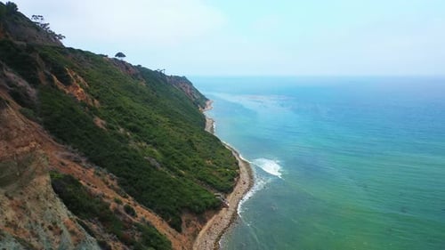 Waves breaking against a rocky shoreline below the rugged terrain of Palos Verdes, California - pull