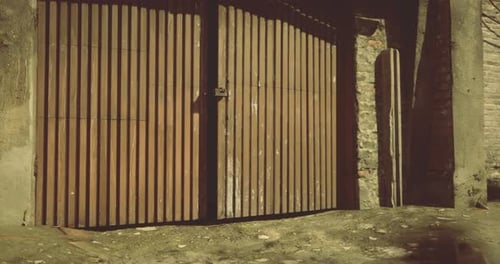Wooden Gate Against a Textured Stone Wall in a Rustic Setting
