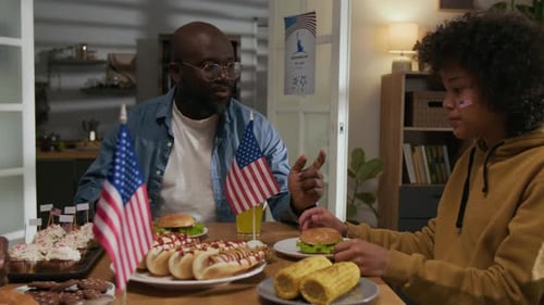 Black Family Chatting and Eating during Fourth of July Home Party