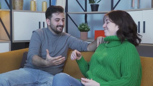 Man and Woman Talking on Sofa Indoors