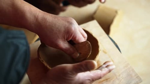 Man shaping clay bowl with tools in studio