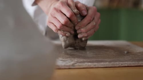 Hands Shaping Clay in Pottery Workshop