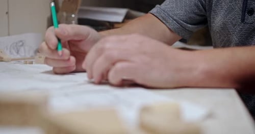 Man Drawing Technical Diagram With Pencil On Paper