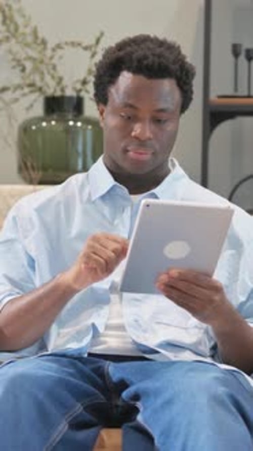 Young Adult Using Tablet Device While Sitting
