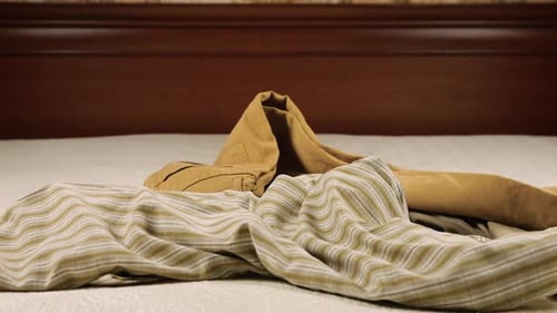 Clothes thrown haphazardly onto a white bedspread