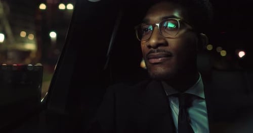 Man Rides in Car Through City at Night