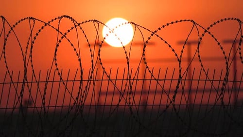 Barbed Wire Fence Silhouetted at Sunset