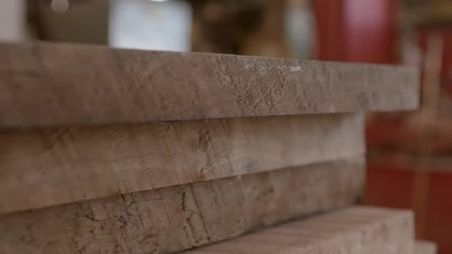 Lumber boards in a stack in a workshop, close up with slow track left