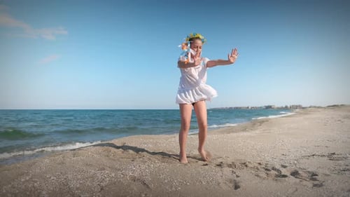 Ukrainian Girl in Shirt with Floral Wreath with Multicolored Ribbons Dances on Coast Near Black Sea