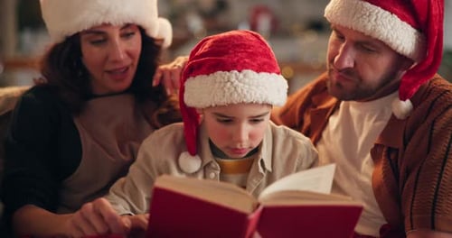 Family Wearing Santa Hats Reading a Book