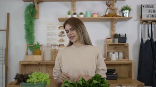 Woman Examining Fresh Greens in Bright Kitchen