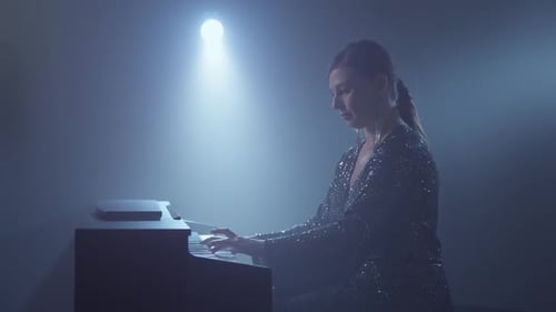 Woman Playing Piano Under Spotlight in Smoky Room