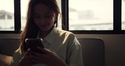 Young Woman Using Smartphone Indoors on Couch