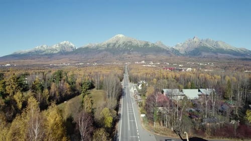 Autumn aerial shot above straight mountain road, view of high mountains, and forests. High Tatras