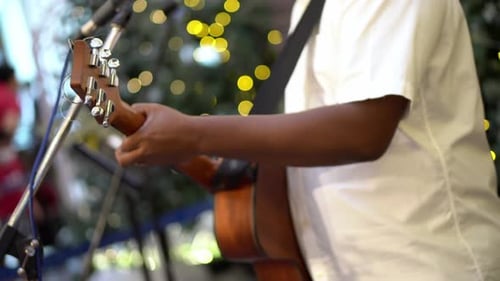 Close up the hand hold guitar and play the song