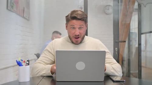 Man Excited About Good News on Laptop in Office