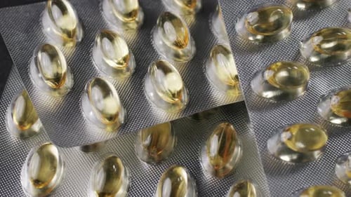 Wrapped Omega Fish Oil Gel Capsules on Black Background Closeup Omega Vitamins Pills 3 6 9 To Be